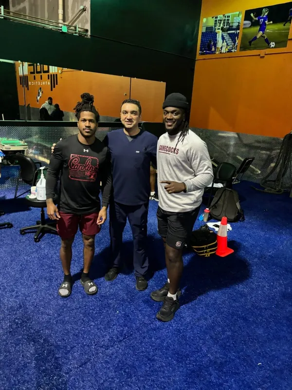 Dr. Manan Patel with two football athletes at a training facility